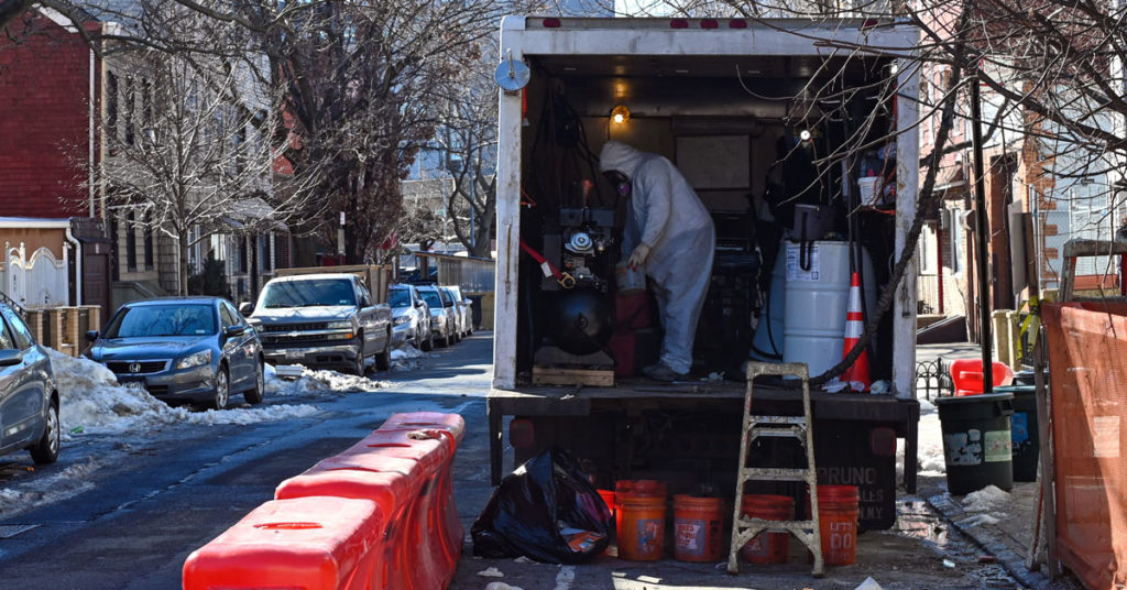 Worker in safety gear handling chemicals in back of truck. | Safer Chemicals