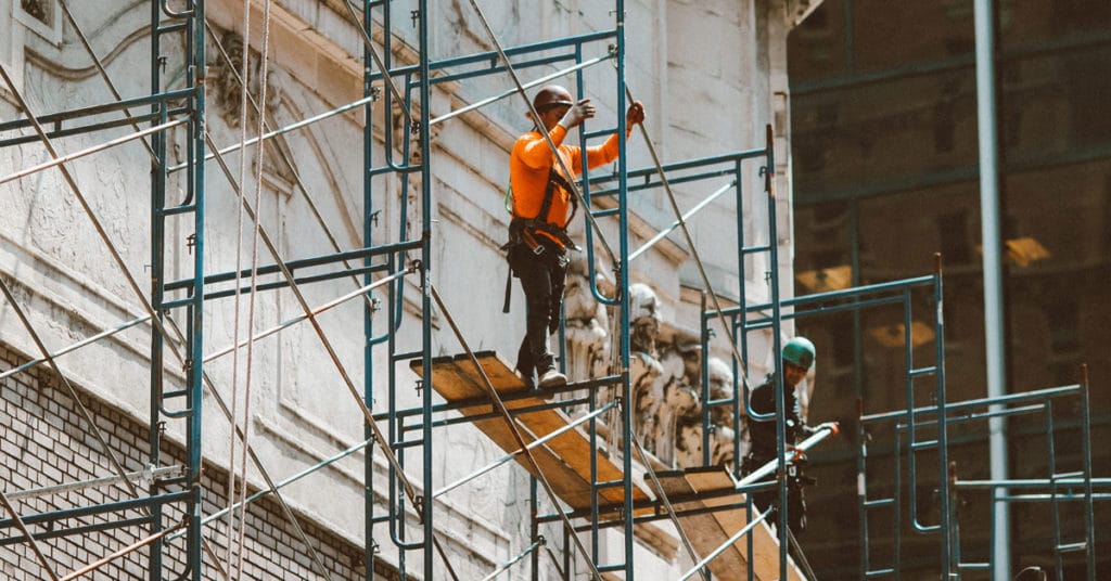 Construction workers standing on scaffolding outside of building | Scaffolding Accidents
