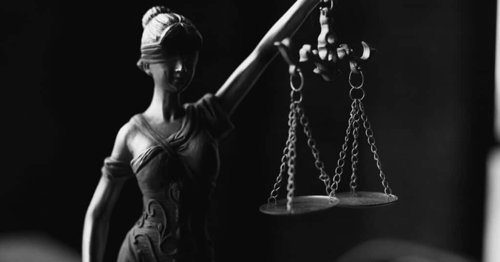 A figurine of a blindfolded woman holding up balanced scales of justice