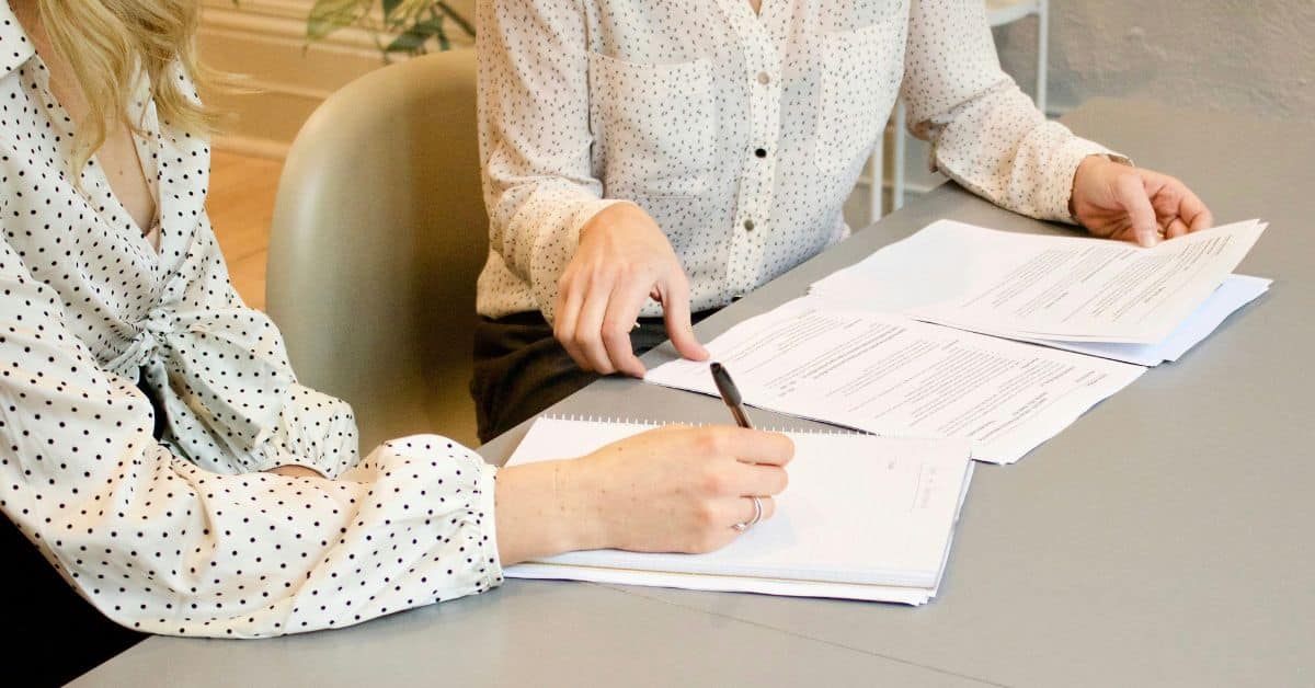 Two people sitting at a table while signing documents, generational wealth estate planning