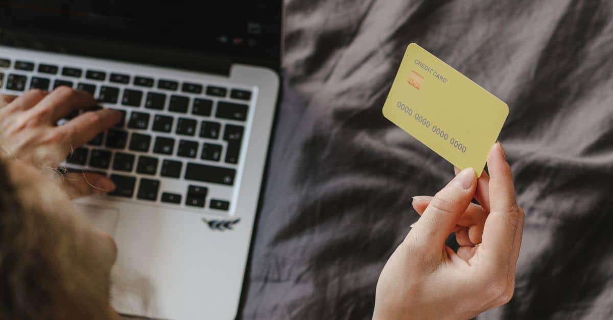 A woman holding a credit card in one hand while typing on a laptop, Mistakes to Avoid in Estate Administration